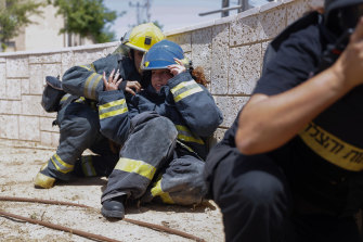 Israeli firefighters take cover as a siren warns of incoming rockets from Gaza.