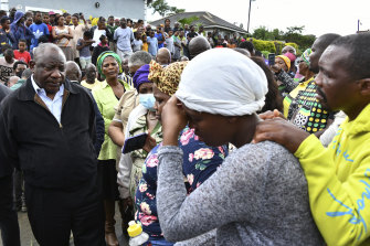 South Africa’s President Cyril Ramaphosa, left, looks at a phone shown by a grieving family member, as part his visit to assess the damage on the outskirts of Durban on Wednesday.
