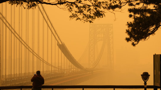 A man talks on his phone as he looks through the haze at the George Washington Bridge in New Jersey, after a wave of fires in Canada blanketed the New York area in smoke.