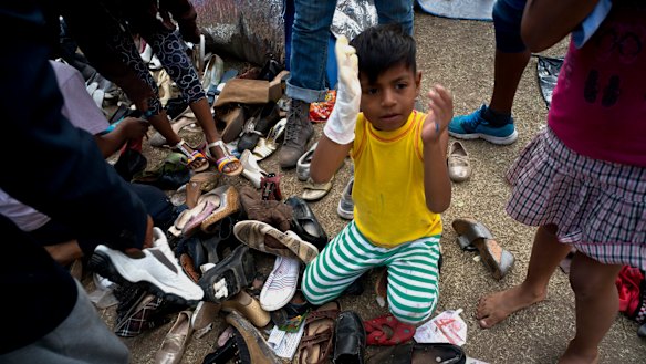 A migrant child holds a hand puppet while sitting on a pile of donated shoes at the Benito Juarez Sports Centre  in Tijuana, Mexico, on Saturday.