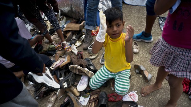 A migrant child holds a hand puppet while sitting on a pile of donated shoes at the Benito Juarez Sports Centre  in Tijuana, Mexico, on Saturday.