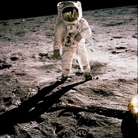 Buzz Aldrin walks on the moon during the first human landing in 1969. Fellow astronaut Neil Armstrong the first to set foot on the moon, is seen reflected in Aldrin’s helmet glass.