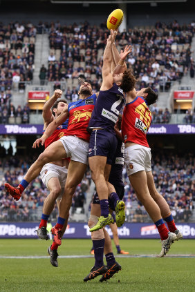 Griffin Logue flies against Lions Marcus Adams and Oscar McInerney for a mark.