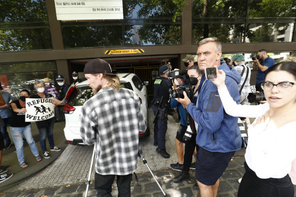 Police officers move media away from a van entering the Park Hotel car park on Saturday afternoon.