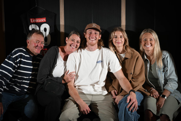 Nathan Murphy sits in front of his locker at Collingwood on Tuesday with parents Shaun and Deborah (left), girlfriend Rose Meech (second from right) and sister Jessica.