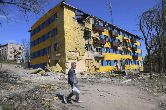 A local resident walks past a destroyed building in Mariupol.