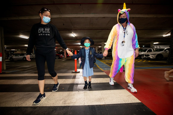 Teachers dressed in unicorn outfits welcome children back to school.