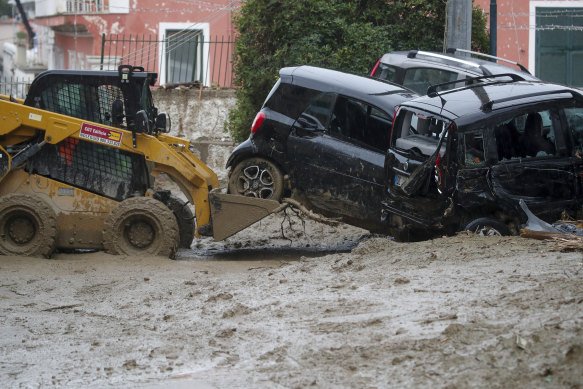 A caterpillar removes damaged cars in a flooded street in Casamicciola, Ischia, on Saturday.