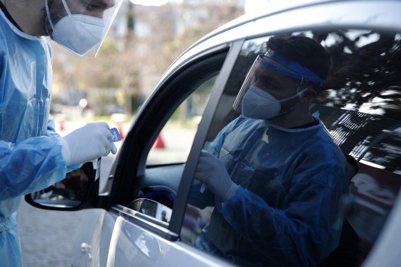 A medical worker conducts a COVID-19 rapid test on a woman at a drive-through testing site in Athens.