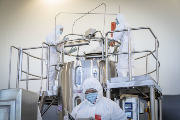 Staff at CSL's Broadmeadows lab with the bioreactor, which will begin making the Oxford-AstraZeneca vaccine from Monday.