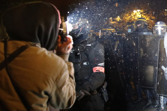 A demonstrator takes a picture of police officers during a protest against the bill restricting images of police.