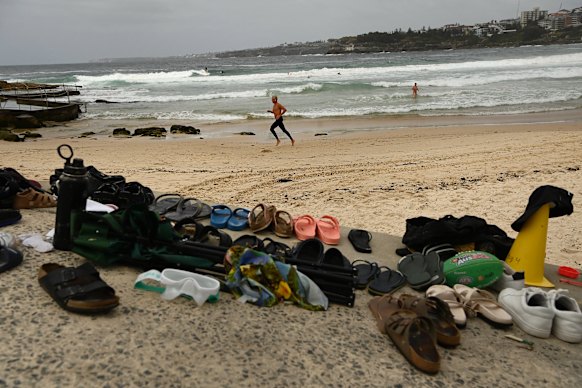 At man runs along Bondi Beach near the abandoned possessions belonging to people who fled Bondi Beach last night.