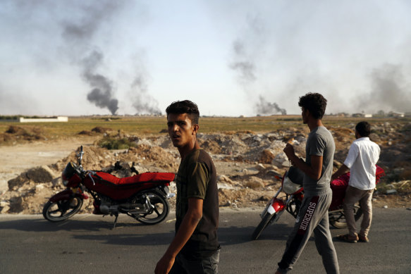 People at the Turkish-Syrian border watch smoke billowing from targets inside Syria during bombardment by Turkish forces.