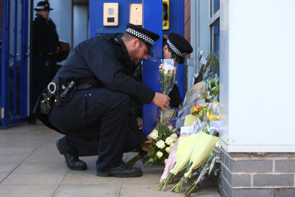 Metropolitan Police collect floral tributes at Croydon Custody Centre following the shooting.