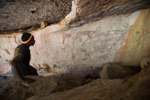 Traditional owner Ian Waina inspects a painting of a kangaroo that is more than 12,700 years old.