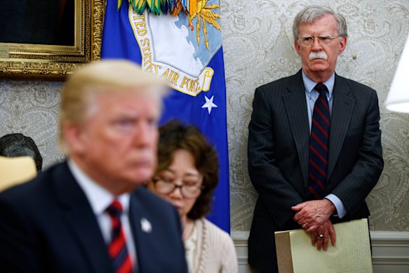 Donald Trump in the Oval Office during his first term with then national security adviser John Bolton watching on.
