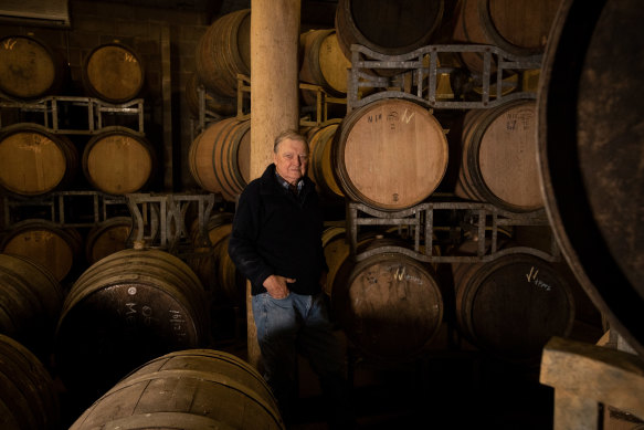Ken Eckersley stands among empty barrels that would normally full of red wine from 2020.