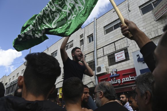 Under a Hamas flag, a demonstrator protests the Israeli bombing of Gaza on the streets of central Ramallah, following Friday prayers.
