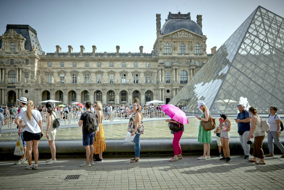 Tourists queue to enter the Louvre Museum in Paris. 