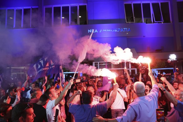 Supporters of Kyriakos Mitsotakis leader of the center-right New Democracy celebrate outside the headquarters of the party in Athens.