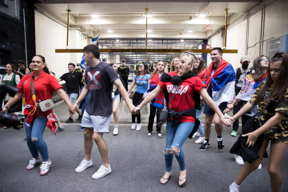 Fans of Novak Djokovic celebrate outside his lawyers’ offices as police guard the building.