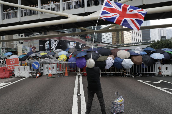 Grandma Wong waves the Union Jack as other protesters use umbrellas to shield themselves outside the Legislative Council in Hong Kong, in June 2019. She says she was detained in August then prevented from returning to Hong Kong.