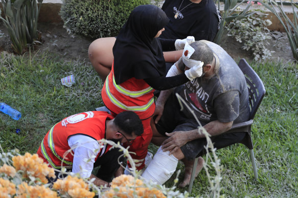 Paramedics treats a man who was injured after an Israeli airstrike hit two adjacent buildings east of the southern port city of Sidon, Lebanon, on Sunday.