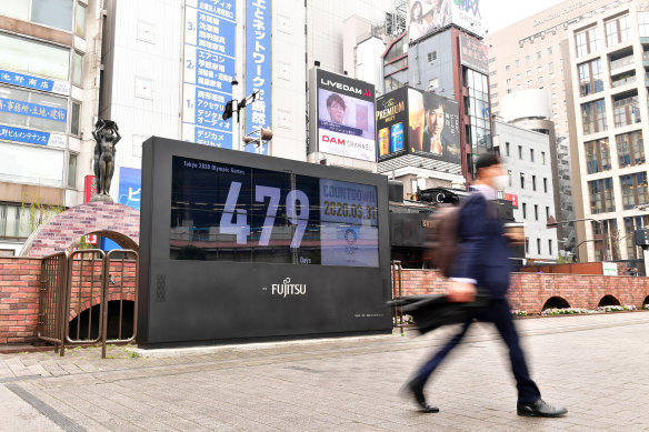 A commuter walks past the reset countdown display of the Tokyo Olympic Games outside the JR Shinbashi Station in Tokyo, Japan.