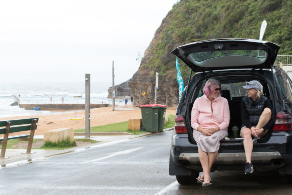 Women sheltering from the rain at Bilgola Beach this morning .