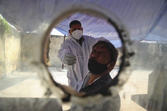 A health worker takes a nasal swab sample at a COVID-19 testing centre in Hyderabad. India has started rolling out a vaccination program.