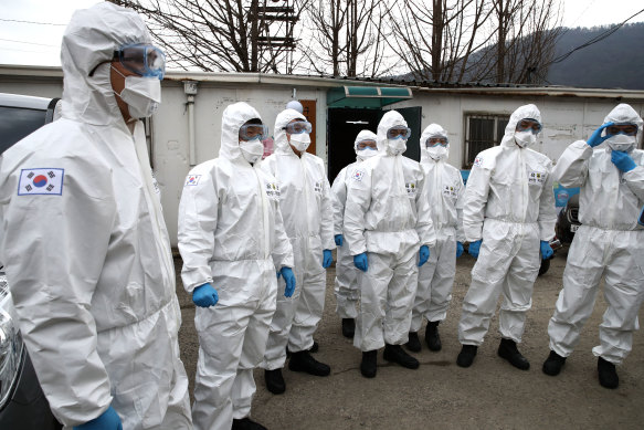 South Korean soldiers wearing protective gear prepare to disinfect against the coronavirus.