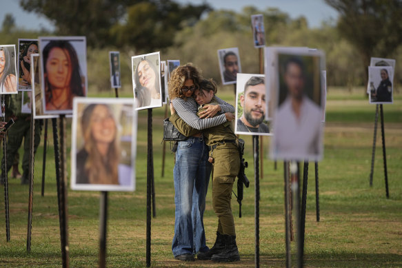 Israelis embrace next to photos of people killed and taken captive by Hamas militants during the attack on the Nova music festival in southern Israel on October 7.