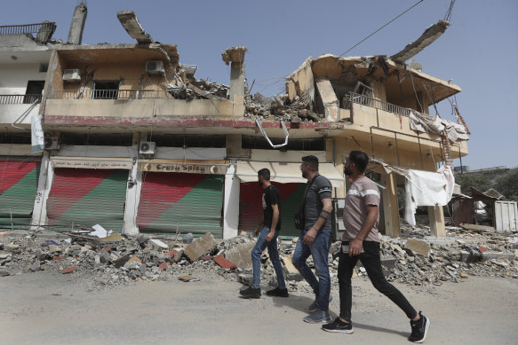 People walk past a building destroyed by Israeli bombing in Kfar Kila, south Lebanon.  Hezbollah militants and Israeli forces have been exchanging fire since a day after the war between Israel and Hamas began on October 7.