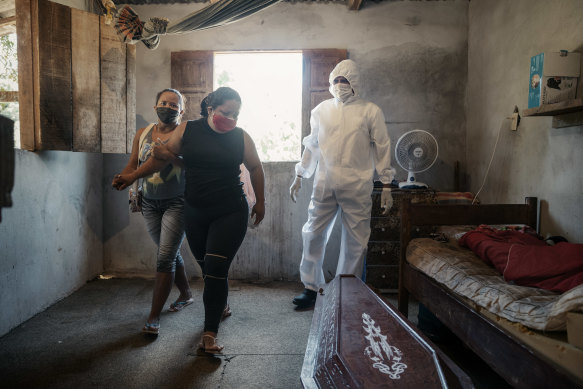 Elen Ferreira do Nascimento is comforted as workers take the body of her mother, who died at home during the coronavirus pandemic, in Manaus.