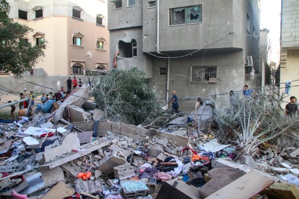 Palestinian emergency services and local citizens search for victims in buildings destroyed during Israeli air raids.