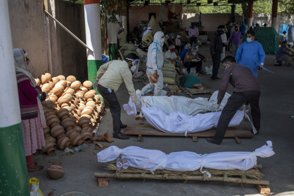 People line up dead bodies of those who died of COVID-19 at a crematorium, in New Delhi.