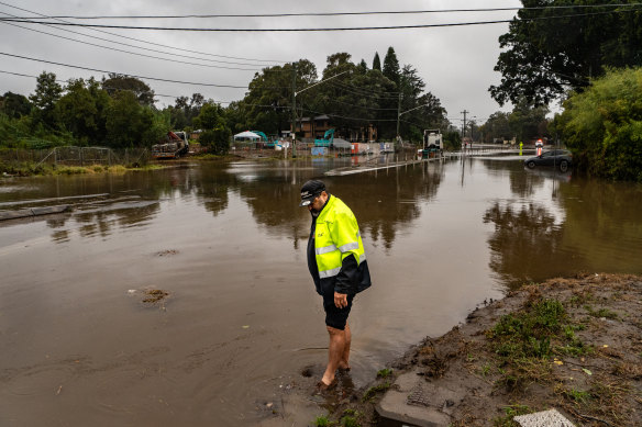 Resident Steve Arnold walks in floodwaters in Moorebank in Western Sydney.