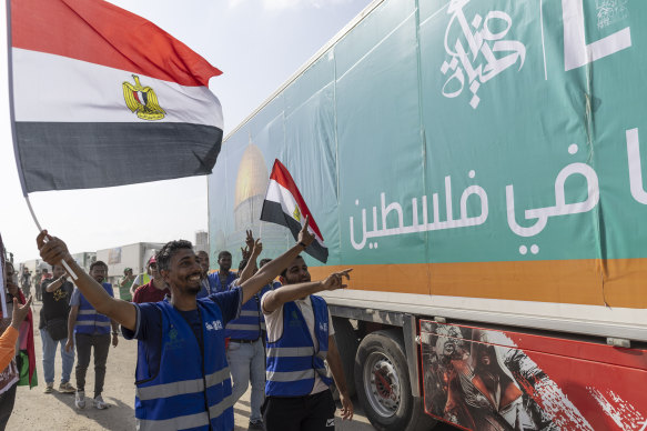 People wave Egyptian flags as the second convoy of aid trucks crosses from the Egyptian side.