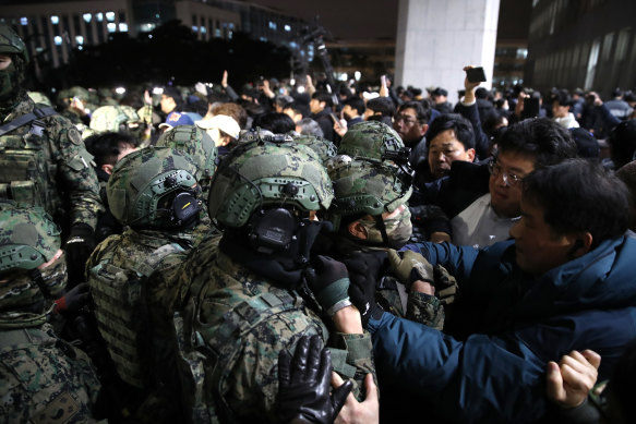 Sending in the troops: South Korean soldiers try to enter the National Assembly building.