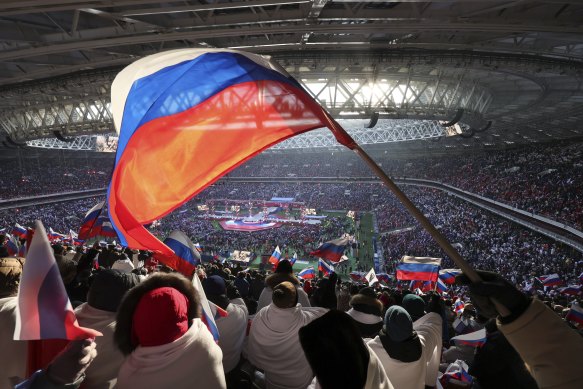 People wave Russian national flags during the Glory to the Defenders of the Fatherland concert, as they wait for Vladimir Putin at the Luzhniki Stadium in Moscow.