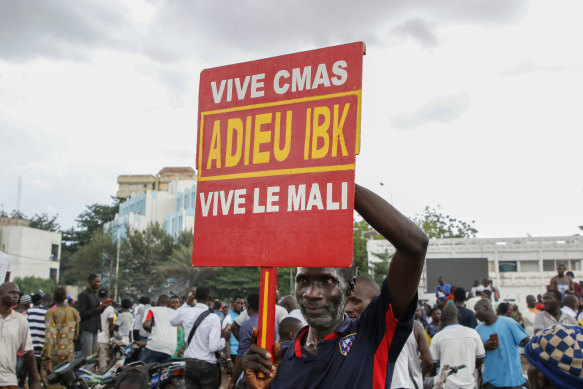 A man holds a sign saying goodbye to IBK, referring to Malian President Ibrahim Boubacar Keita, as soldiers parade in the capital on Tuesday.