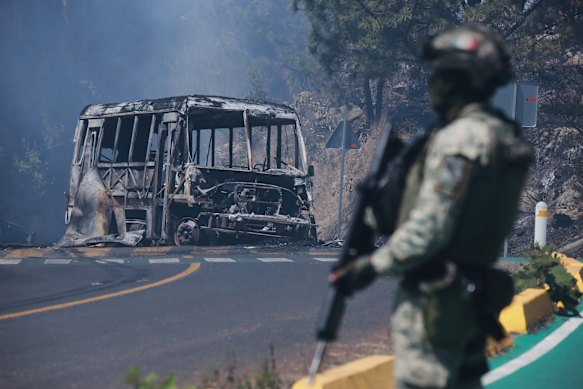 A soldier stands guard by a charred vehicle after it was set on fire in Cointzio, Michoacán state, Mexico, after the death of the leader of the Jalisco New Generation Cartel, Nemesio Rubén Oseguera Cervantes, known as “El Mencho”.