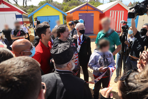 Novak Djokovic at Brighton Beach after winning the Australian Open in 2021. Bobby Sibic, who has been referred to as the Australian Night Wolves’ president, stands in front of Djokovic and is holding the Night Wolves flag.