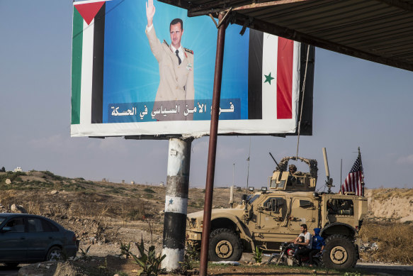 US military convoy drives the he town of Qamishli, north Syria, by a poster showing Syrain President Bashar Aassad on Saturday.