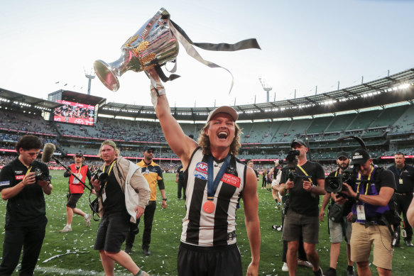 Jack Ginnivan celebrates with the premiership cup after a surprise appearance at the races on grand final eve.