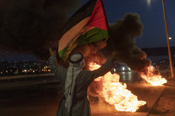A protester flies a Palestinian flag during clashes with Israeli troops in Nablus this month.