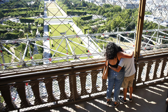 Two people hug on the Eiffel Tower in Paris. 