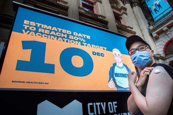 Recently vaccinated Edbert Limen poses in front of the big screen at Melbourne Town Hall displaying Victoria’s vaccination tally on Thursday. 