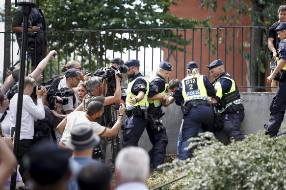 Police members try to restrain a man outside Stockholm’s mosque at Medborgarplatsen in July. 