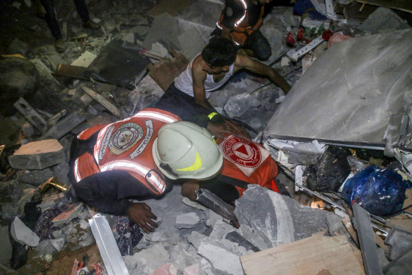 Members of the Palestinian Civil Defense search for people trapped under a destroyed house.